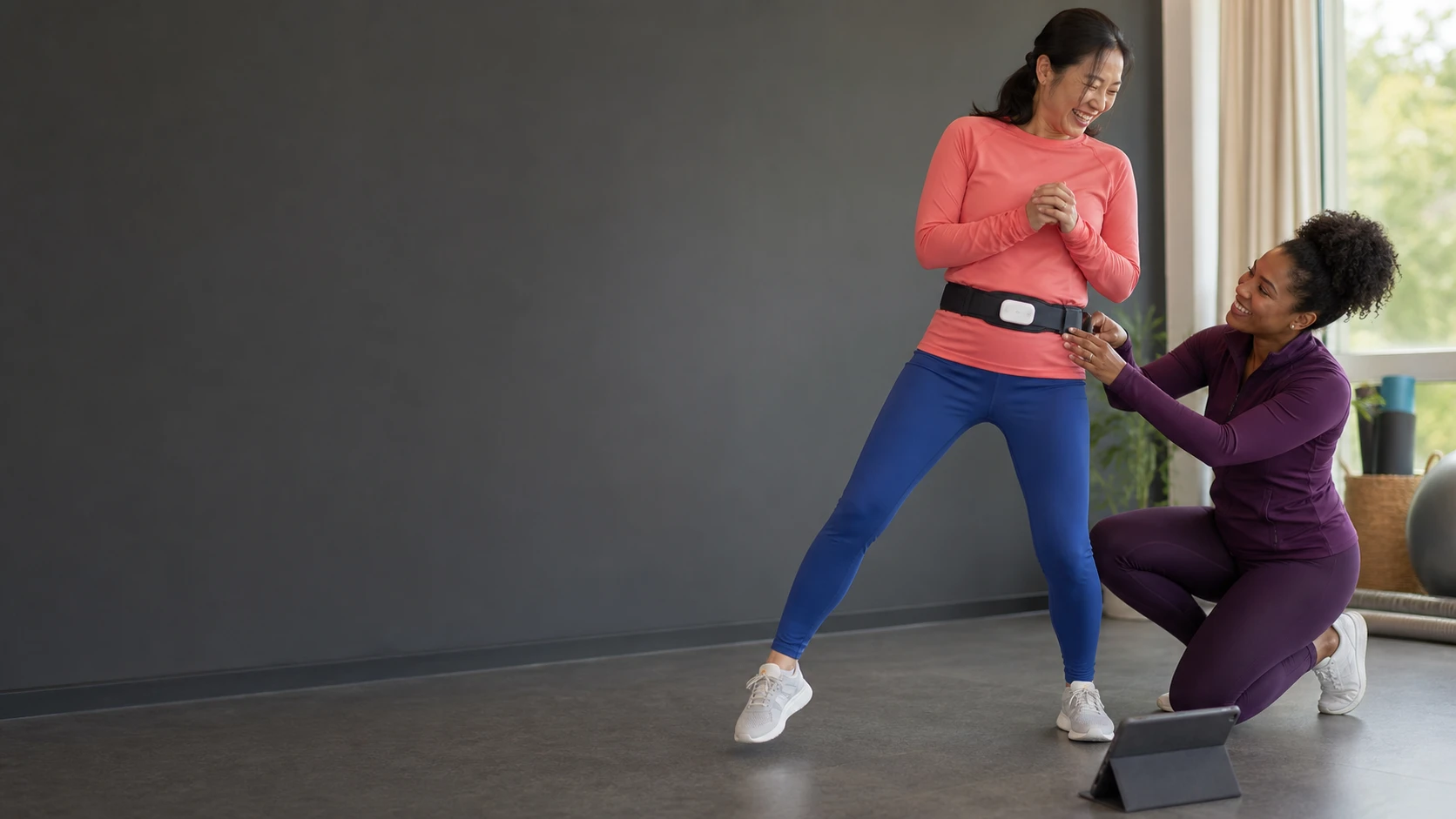 A woman uses a waist biofeedback sensor during a guided movement session with her physiotherapist